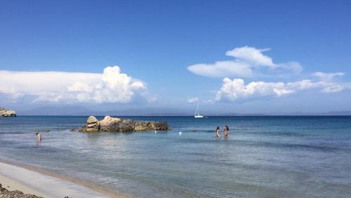 a group of people standing in the water on a beach at Le Case di Loris in SantʼAntìoco