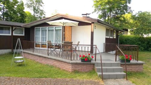 a house with a porch with a table and an umbrella at Domki i pokoje - "KAMERALNY przy promenadzie" ul Wczasowa 2 in Charzykowy