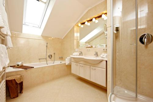 a bathroom with a tub and a sink and a shower at Staudacherhof in Garmisch-Partenkirchen I Blick aufs Zugspitzmassiv I einzigartige Bayurvida Küche in Garmisch-Partenkirchen