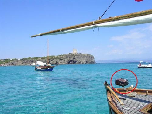 a boat in the water with an island in the background at Le Case di Loris in SantʼAntìoco