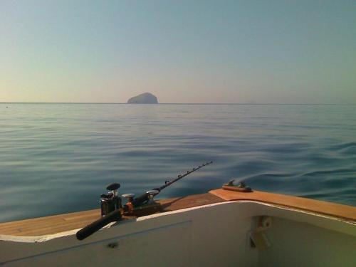 a boat with a fishing pole on the water at Le Case di Loris in SantʼAntìoco