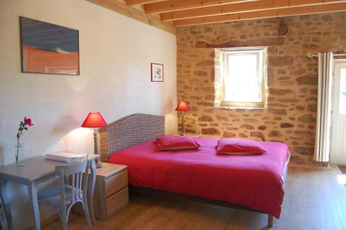 a bedroom with a red bed and a table and a desk at Le Pont St Michel in Les Portes du Coglais