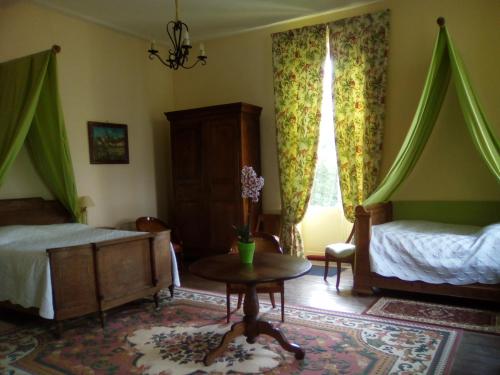 a bedroom with two beds and a table and a window at Chambres d'hôtes & Gîtes du Château de Grand Rullecourt in Grand Rullecourt