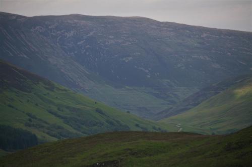 a green hillside with a mountain in the background at The Little Houses in Roybridge