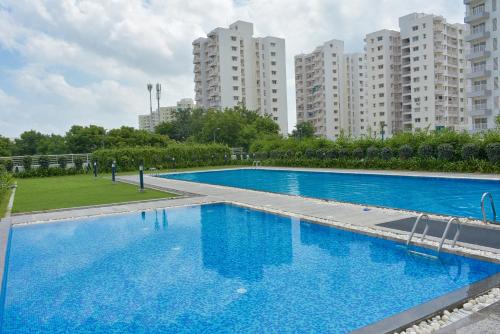 a large blue swimming pool with tall buildings in the background at LE Chalet - Serviced Luxury Condominium in Ahmedabad