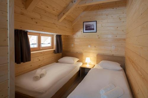 two beds in a log cabin with a window at 1861 Blejka apartments Bled in Bled