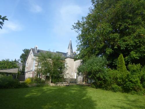 an old house with a church with a grass yard at La Nouvelle Criqueboise in Criquebeuf-en-Caux