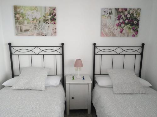 two twin beds in a bedroom with a night stand at Casa Corina. Primera línea de mar in Punta Mujeres