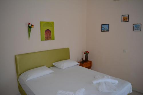 a bedroom with a white bed with a green headboard at Kangaroo Hotel in Mola Kalyva
