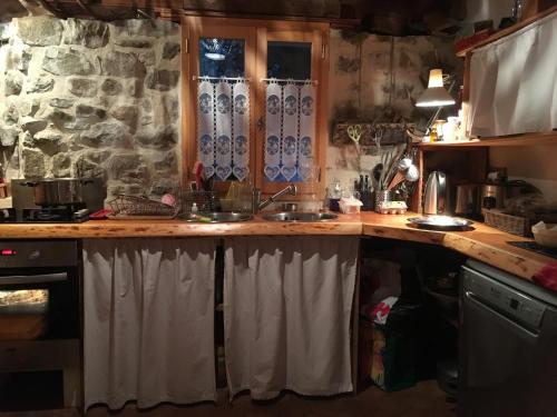 a kitchen with a sink and a stone wall at Les Murets in Colmars