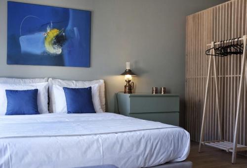 a bedroom with a bed with blue pillows and a painting at Flats 323 apartments in Porto