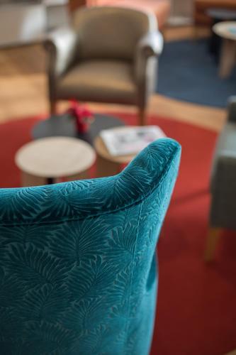 a blue chair sitting in a room with a table at James Boutique Hôtel Colmar centre in Colmar