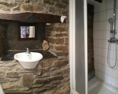 a bathroom with a sink and a stone wall at Pensión Albergue A Pedra in Sarria