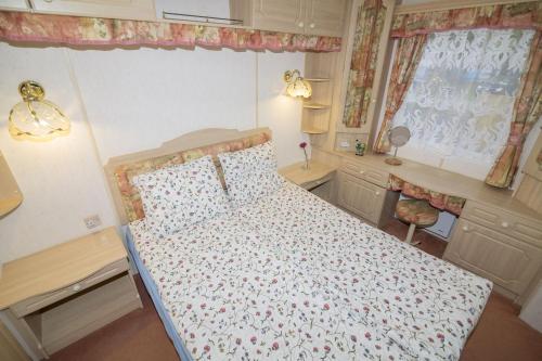 a small bedroom with a bed with a floral bedspread at Domki Delux w Helu in Hel