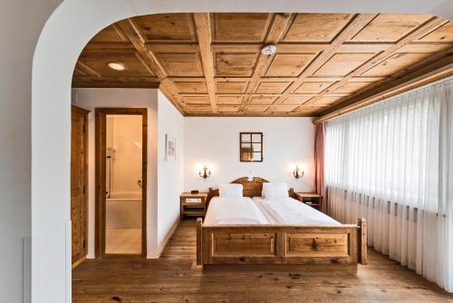 - une chambre avec un grand lit et un plafond en bois dans l'établissement Hotel Restaurant Chesa, à Flims