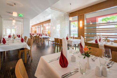 a restaurant with white tables and chairs with red vases at Best Western Hotel Am Straßberger Tor in Plauen