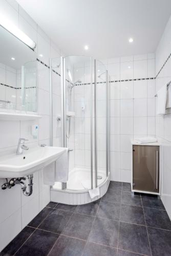 a white bathroom with a sink and a shower at Laimer Hof am Schloss Nymphenburg in Munich