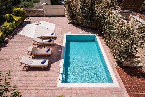 an overhead view of a swimming pool with chairs and an umbrella at Spilia Village Hotel & Villas in Spiliá