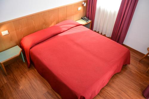 a red bed with a red blanket in a room at Hotel Sport in Ledro