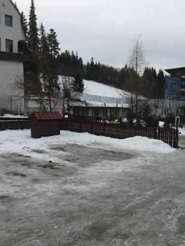 ein Parkplatz mit Schnee und einem Zaun in der Unterkunft Spa-ul Schiorilor in Predeal