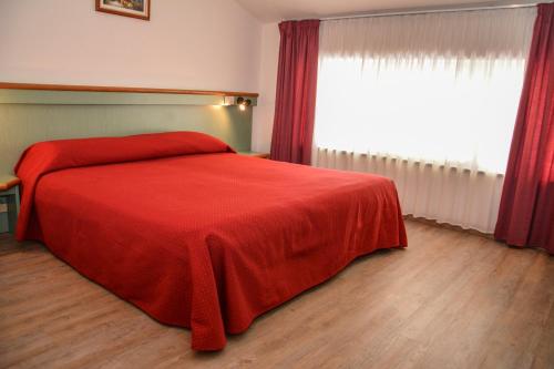 a bedroom with a red bed with a red blanket at Hotel Sport in Ledro