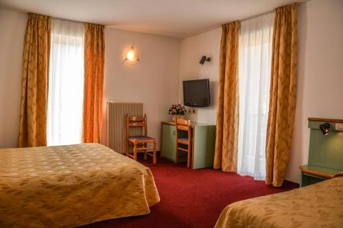 Cette chambre comprend deux lits et une télévision. dans l'établissement Hotel Sport, à Ledro