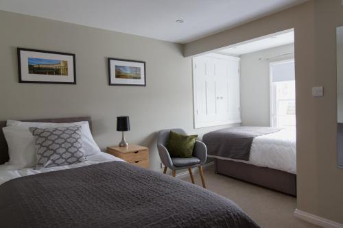 a bedroom with two beds and a chair and a window at Osric Apartment in Bath