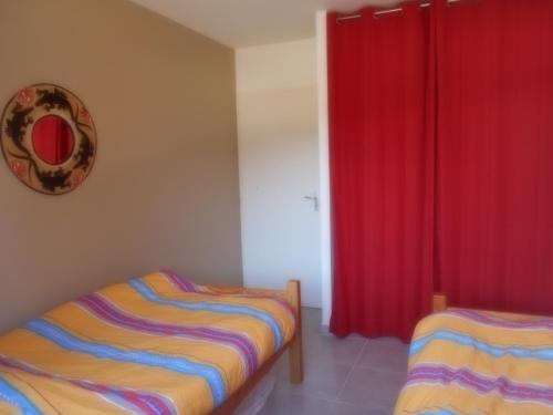 Coeurs fidèles في فالون بون دارك: غرفة نوم بسريرين وستائر حمراء