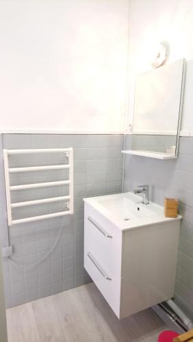 une salle de bain blanche avec un lavabo et un miroir dans l'établissement Studio cosy proche Gare, à Libourne