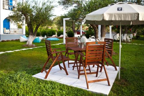 a wooden table and chairs under an umbrella at Sun 'n Chill, Boutique Apartments & Beach Villa in Melíkia