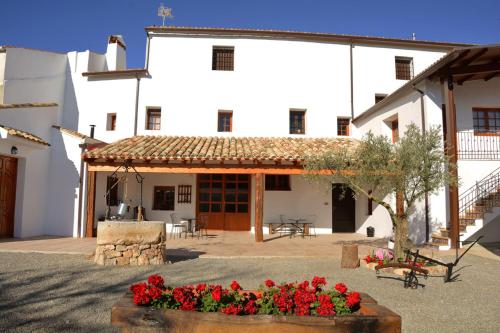 um grande edifício branco com um pátio com flores vermelhas em Casa Rural Aromas de la Manchuela em Alborea