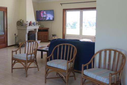 a living room with a blue couch and two chairs at Casa das Oliveiras in Beiral do Lima