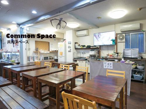 a restaurant with wooden tables and chairs and a kitchen at Hotel Raizan South in Osaka