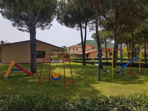 a playground in a yard with trees and a building at Lido Azzurro Residence in Capoliveri
