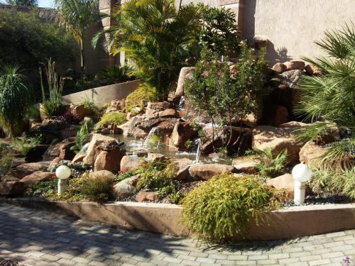 a garden with a waterfall and rocks and trees at Bubez Guesthouse in Barberton