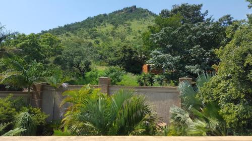 a fence with trees and a mountain in the background at Bubez Guesthouse in Barberton