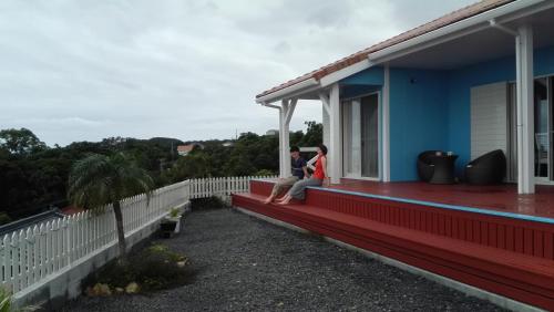 two people sitting on the porch of a house at Yakushima Pension Luana House in Yakushima