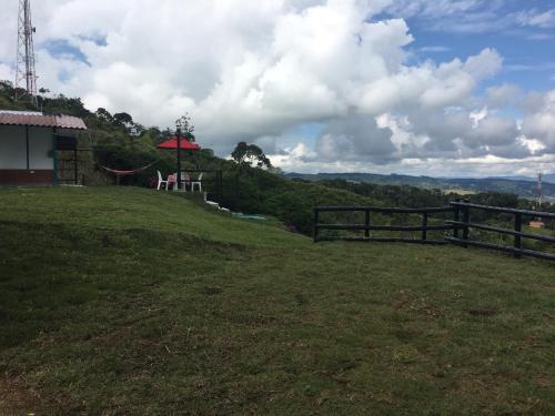 a grassy hill with a fence and a red umbrella at La cabaña del lago Calima in Calima