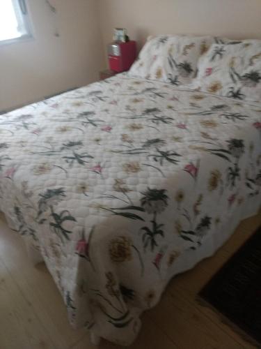 a bed with a white blanket with flowers on it at Hospedagem Amanhecer in Barreirinhas