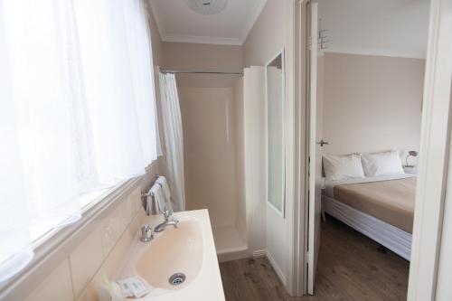 a white bathroom with a sink and a bed at BIG4 Moama Holiday Park in Moama
