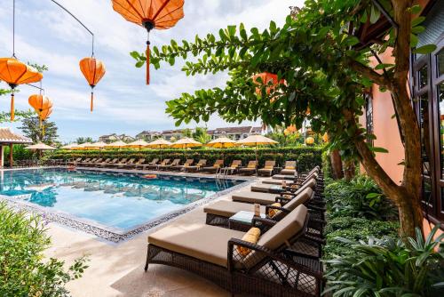 a row of lounge chairs next to a swimming pool at Allegro Hoi An . A Little Luxury Hotel & Spa in Hoi An