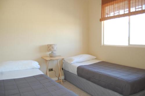 2 Betten in einem Zimmer mit einem Fenster und einem Tisch in der Unterkunft Tronador I in Puerto Montt