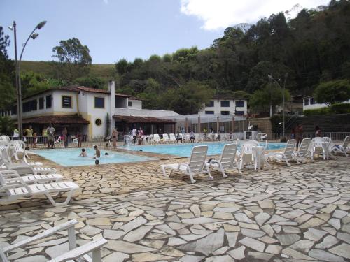 una piscina con sillas blancas y gente en ella en Hotel Miguel Pereira, en Miguel Pereira