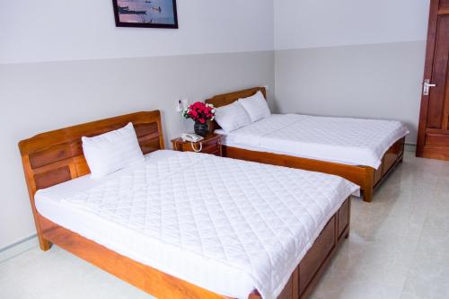 two beds in a small room with flowers in a room at Hoang Thinh Hotel in Kon Tum