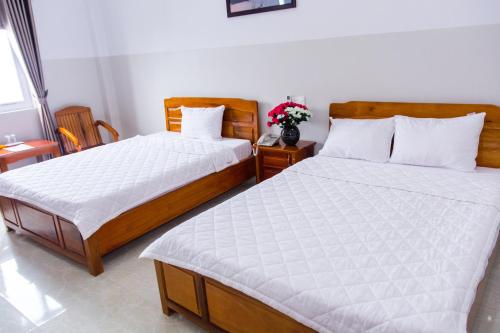 a bedroom with two beds and a vase of flowers at Hoang Thinh Hotel in Kon Tum