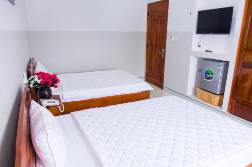two beds in a small room with a tv at Hoang Thinh Hotel in Kon Tum
