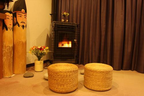 Sala de estar con 2 taburetes y chimenea en Oyado Uchidaya en Nozawa Onsen