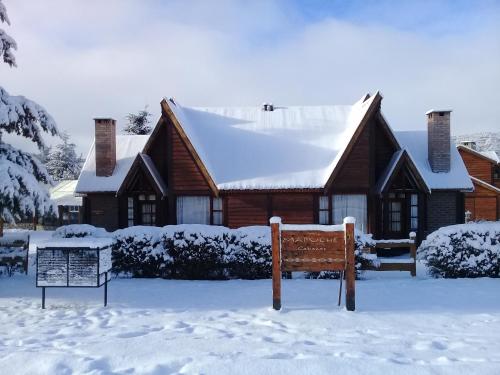a house covered in snow with a sign in front of it at Cabañas Mapuche in Esquel