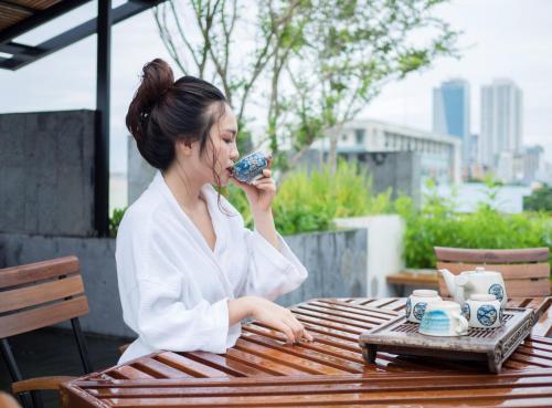 a woman sitting at a table eating a doughnut at Mai's Boutique in Da Nang