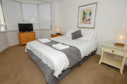 a bedroom with a large white bed and a television at Bond 1603 Self Catering in Sydney